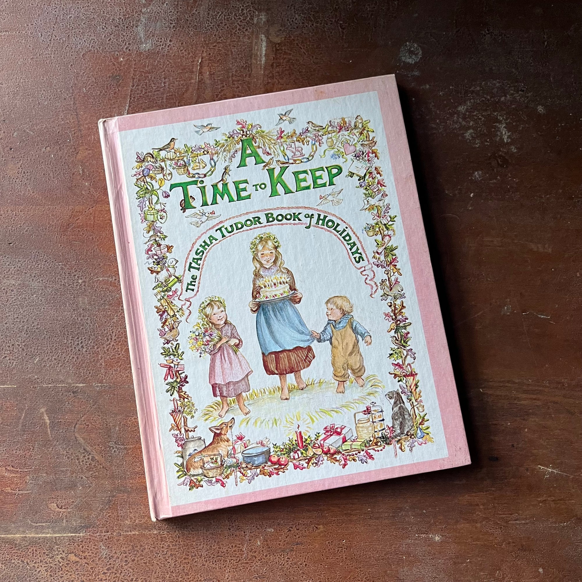 vintage children's picture book - A Time to Keep The Tasha Tudor Book of Holidays written and illustrated by Tasha Tudor - view of the front cover with three children illustrated on it with a border with all kinds of animals tucked into it