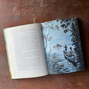 vintage mystery book for children - Alfred Hitchcock's Haunted Houseful written by Alfred Hitchcock with illustrations by Fred Banbery - view of the full page illustrations - this one is of two boys in a canoe paddling towards a small island