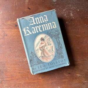 classic literature, Russian Literature, Top 100 Must Read Classic Literature Book - A vintage edition of Anna Karenina written by Leo Tolstoy with illustrations by Fritz Eichenberg sit on a patinaed wood table with the view of the dust jacket's front cover shown
