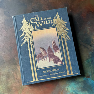 Call of the Wild by Jack London-1987 Portland House Illustrated Classics Edition-Classic American Literature-vintage chapter book-view of the front cover with embossed title & pine trees, illustration of dog howling in the snow