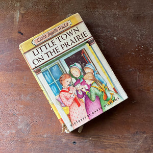 vintage children's chapter book-Newbery Honor Book - Little Town on the Prairie with dust jacket written by Laura Ingalls Wilder with illustrations by Garth Williams - view of the dust jacket's front cover with Mary holding a kitten surrounded by other girls