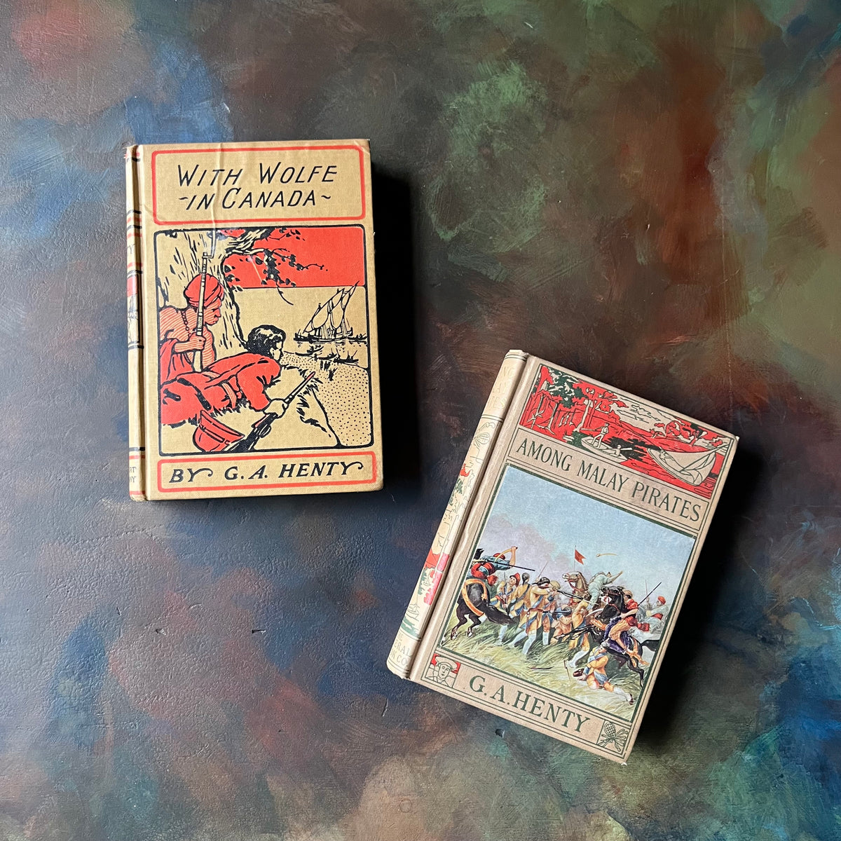 Pair of G. A. Henty Books:  With Wolfe in Canada and Among Malay Pirates-antique children's adventure chapter books-view of the front covers - embossed