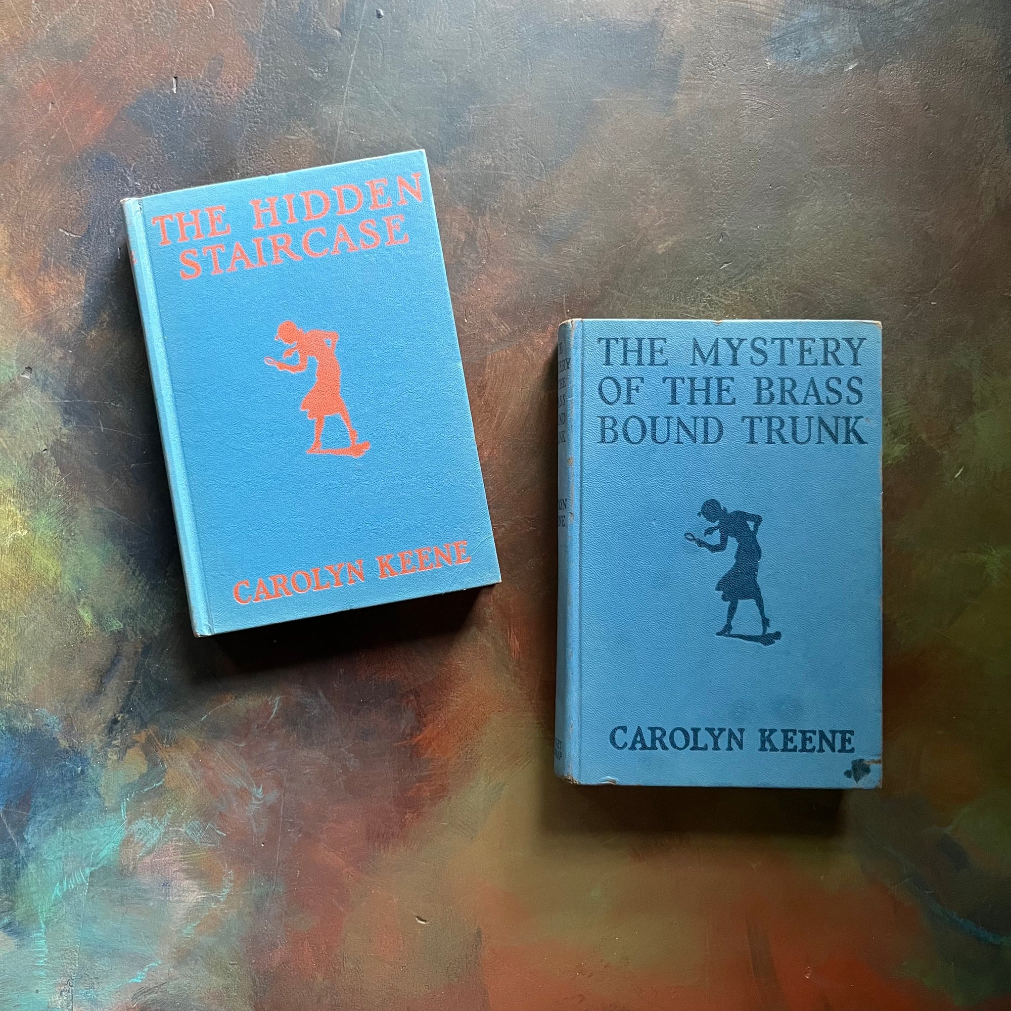 Pair of Nancy Drew Mysteries-The Hidden Staircase & The Mystery of the Brass Bound Trunk-Carolyn Keene-antique children's chapter books-view of the embossed front covers in blue with blue embossing & orange embossing