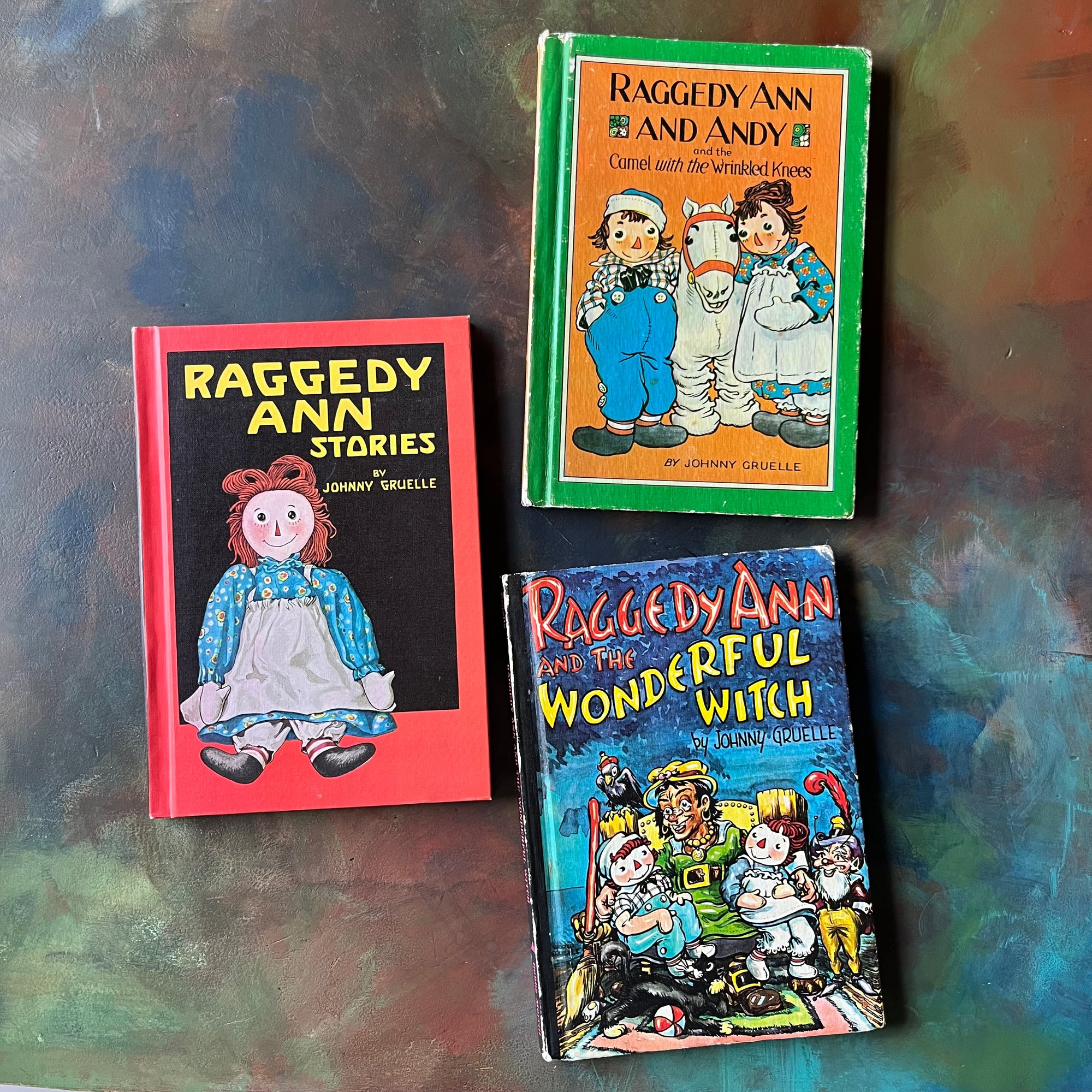 Set of Three Raggedy Ann Books by Johhny Gruelle-Raggedy Ann Stories, Raggedy Ann & Andy & the Camel with the Wrinkled Knees & Raggedy Ann and the Wonderful Witch-view of the front covers in red, blackblue & green & orange with illustrations by Johnny Gruelle-vintage children's storybooks-view of the front covers