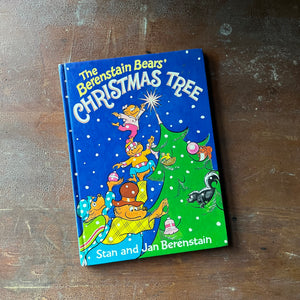 vintage children's picture book, 1980's Children's Literature - The Berenstain Bears' Christmas Tree written & illustrated by Stan and Jan Berenstain - view of the glossy front cover with an illustration of the Berenstain Bear Family lighting a candle at the top of their Christmas Tree