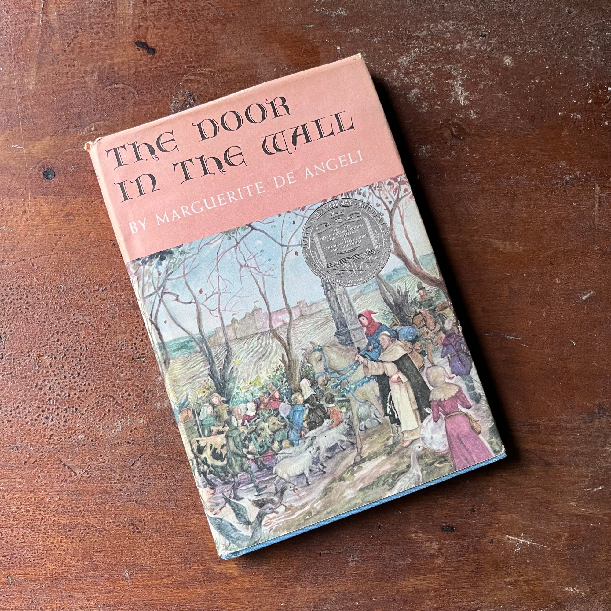 vintage children's chapter book, Newbery Medal Winner - The Door in the Wall written & illustrated by Marguerite De Angeli - view of the dust jacket's front cover with the Newbery Medal Award Emblem in Silver