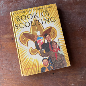 The Golden Anniversary Book of Scouting-the National Council of the Boy Scouts of America-vintage boy scout guide-view of the front cover in yellow with three boy scouts in uniform with the boy scout emblem behind them.