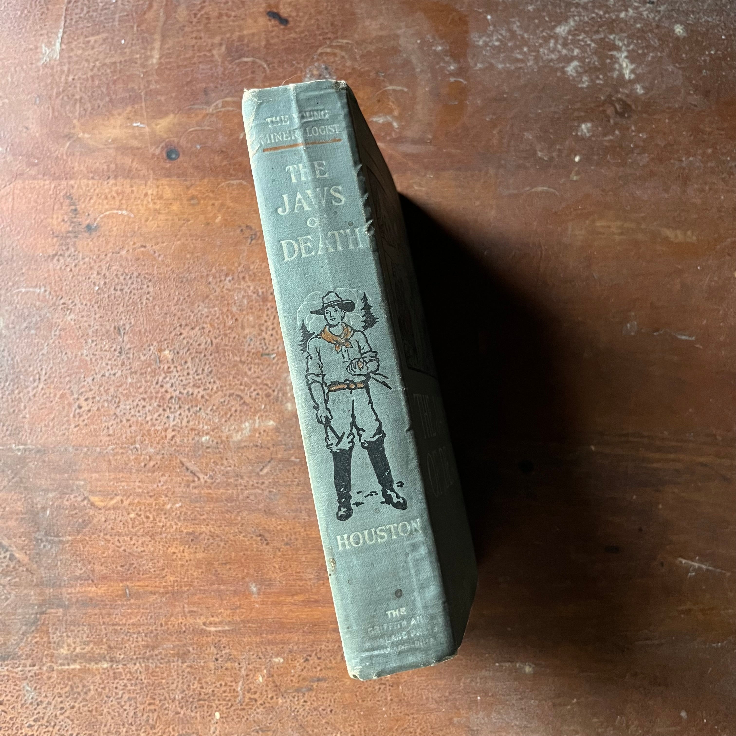 vintage children's chapter book, adventure books for boys - The Young Mineralogist: The Jaws of Death written by Edwin J. Houston - view of the spine with a man holding gold & a small pick