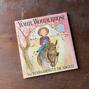 Yonie Wondernose written and illustrated by Marguerite De Angeli-A Caldecott Honor Book-vintage children's picture book-view of the dust jacket's front cover with an image of Yonie riding a horse with the caldecott medal on the cover (not a sticker - it is part of the image of the front cover)