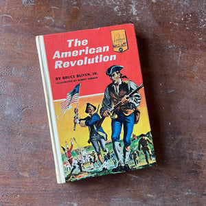 Log Cabin Vintage – vintage children’s book, children’s book, chapter book, living history book, history book, non-fiction, Landmark Series Book –The American Revolution by Bruce Bliven, Jr. - view of the front cover showing the colonial army during battle with a soldier carrying the Betsy Ross Flag