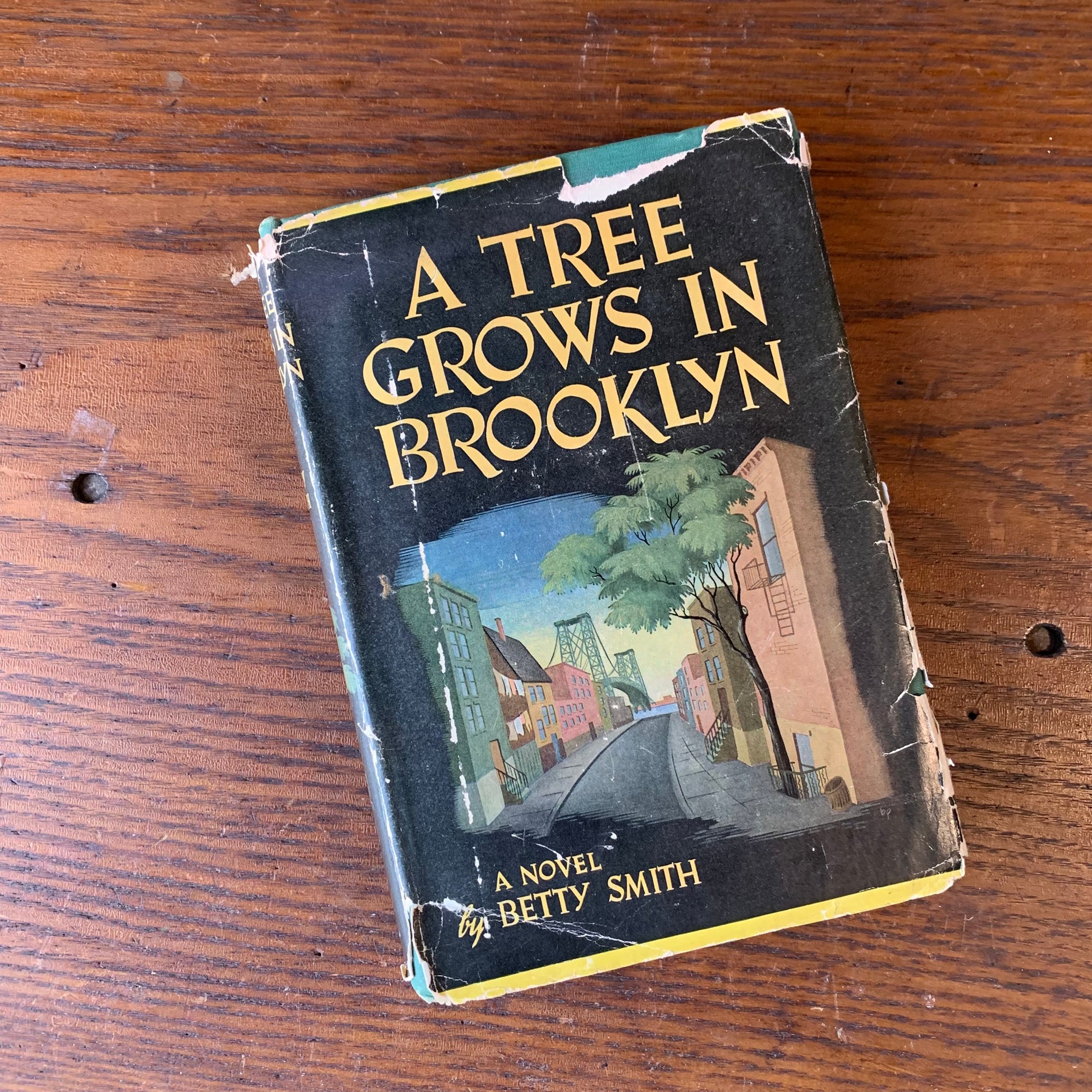 Log Cabin Vintage - vintage fiction, American Author, American novel - A Tree Grows in Brooklyn by Betty Smith - view of the book on a wood table showing the dust jacket's front cover