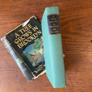 Log Cabin Vintage - vintage fiction, American Author, American novel - A Tree Grows in Brooklyn by Betty Smith - view of the book on a wood table showing the book's spine with the dust jacket laying flat on the table